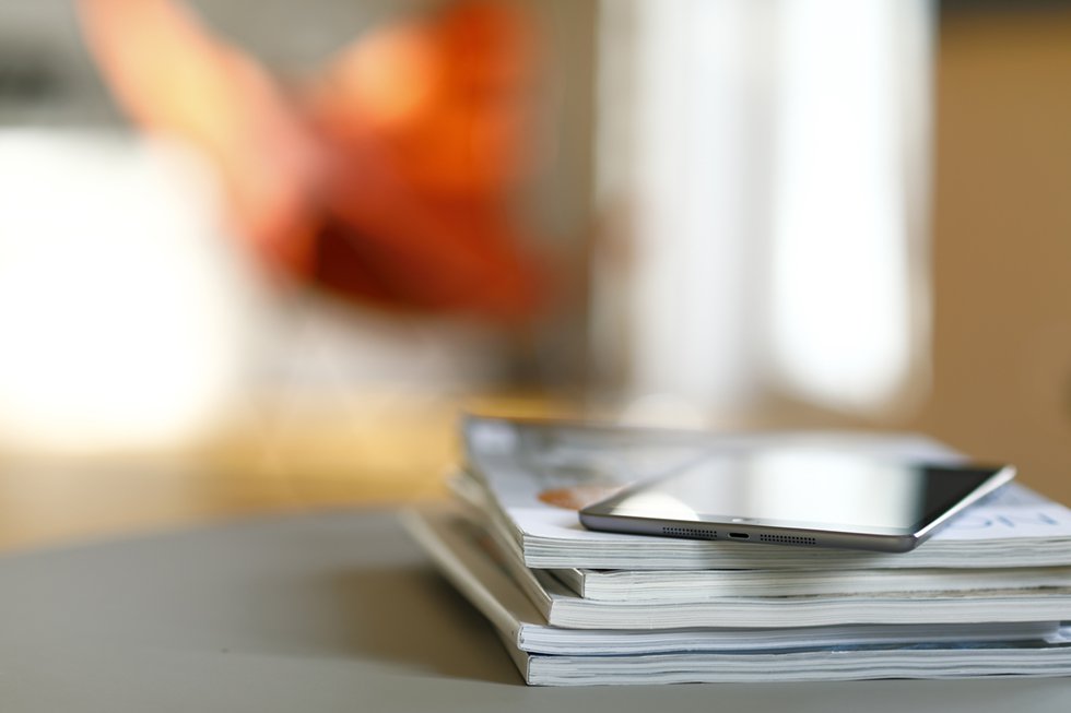 An iPad on top of a stack of magazines.